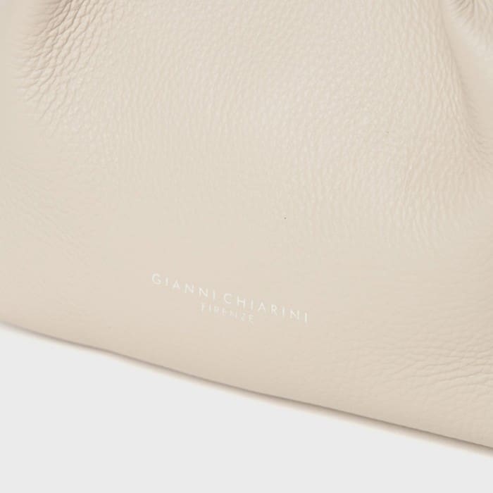 Un gros plan de la surface en cuir beige clair texturé mettant en valeur le savoir-faire raffiné des Giannicchiarini italiens. Près du centre du bas, il y a une petite lettre blanche en relief avec les mots « GIANNI CHIARINI FIRENZE ».